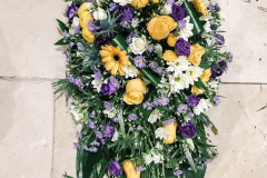 Coffin spray created using a mix of yellow, purple & white flowers.