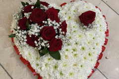 Closed heart with white base flowers, red ribbon edging & complete with a red rose spray.