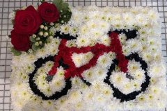 bike funeral tribute presented on a white flower base. Completed with a red rose spray.