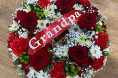 Red rose funeral wreath. Finished with a red ribbon Grandpa sash