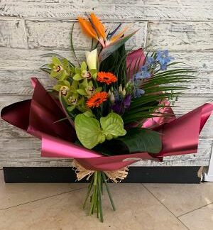 A handtied bouquet showing a mix of exotic flower presented in a luxury wrap with bow