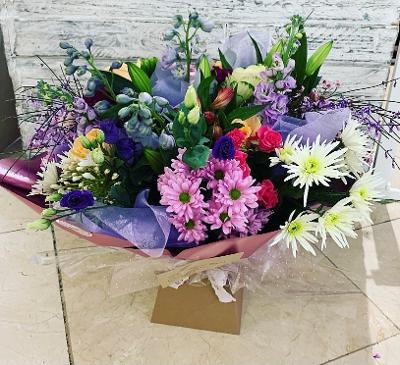 Aqua Bouquet with a mix of seasonal bright flowers in pink, creams, purple. oranges & yellows.