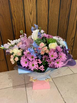 Pretty mix of pastel colour seasonal blooms in a baby pink aqua box with soft blue wrap.