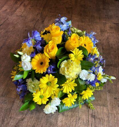 A funeral posy in a round dome shape. Filled with mixed flowers and foliage in colours of your choice.