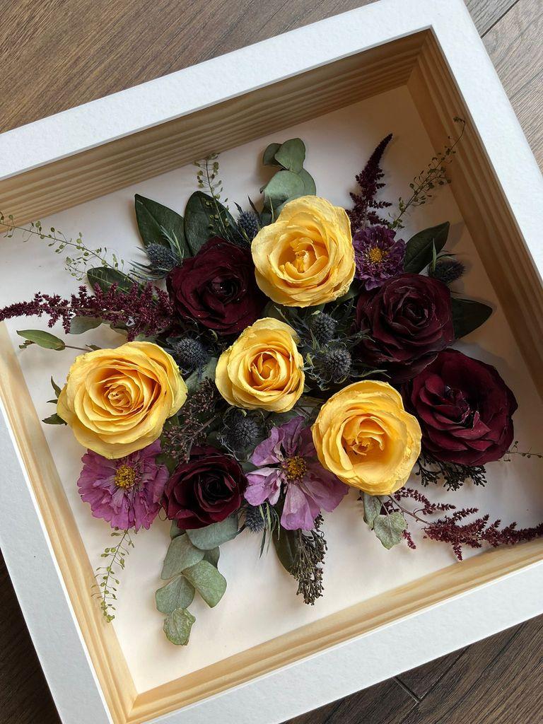 image of preserved flowers in a white box frame.